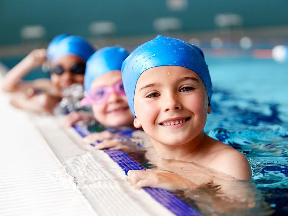 Vier Kinder im Schwimmbecken Vier Kinder im Schwimmbecken, die sich am Rand festhalten