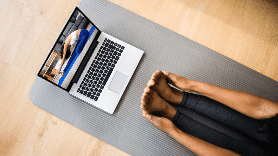 Teilnehmerin macht Bedtime-Yoga vor Laptop im Online-Präventionskurs des Sportvereins Köln-Ehrenfeld