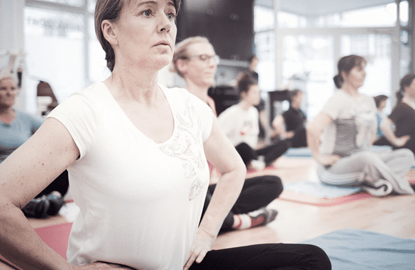 Teilnehmende sitzen auf Matte im konzentrierten Hatha-Yoga-Präventionskurs in Köln-Ehrenfeld
